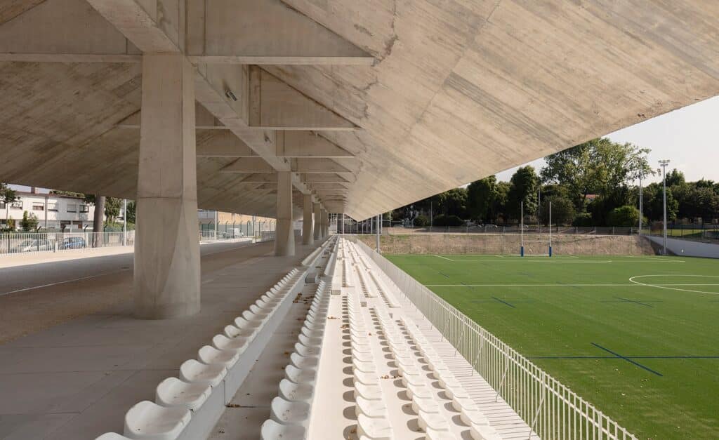 Interior view from the concrete grandstand at Ramalde Sports Park overlooking the green multi-purpose field.