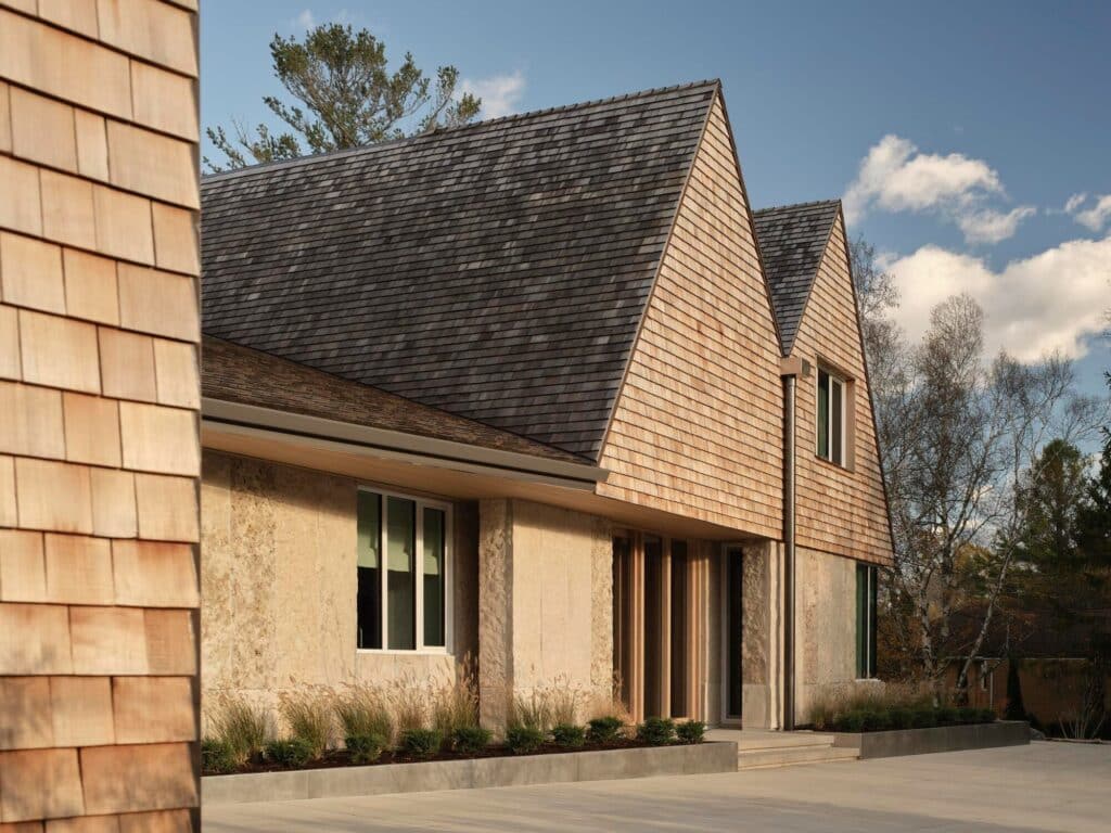 Side perspective of the Georgian Bay beach house showing the rhythmic texture of cedar shingles and integrated large glass windows.