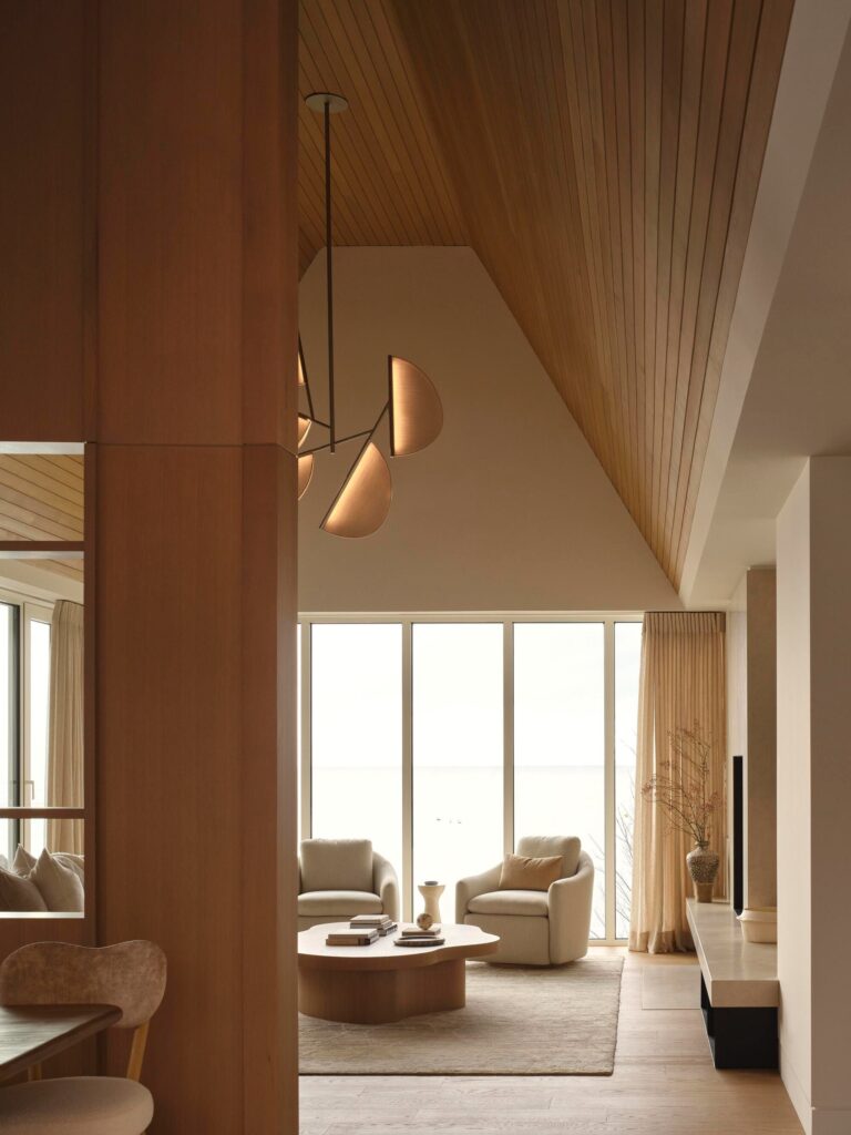 Modern interior living room with high vaulted ceilings, minimalist furniture, and floor-to-ceiling windows overlooking Georgian Bay.