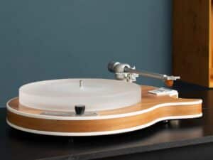 Side view of a Clearaudio Celebrity Al Di Meola Edition turntable featuring a wood-finished guitar-shaped chassis and a thick frosted acrylic platter.