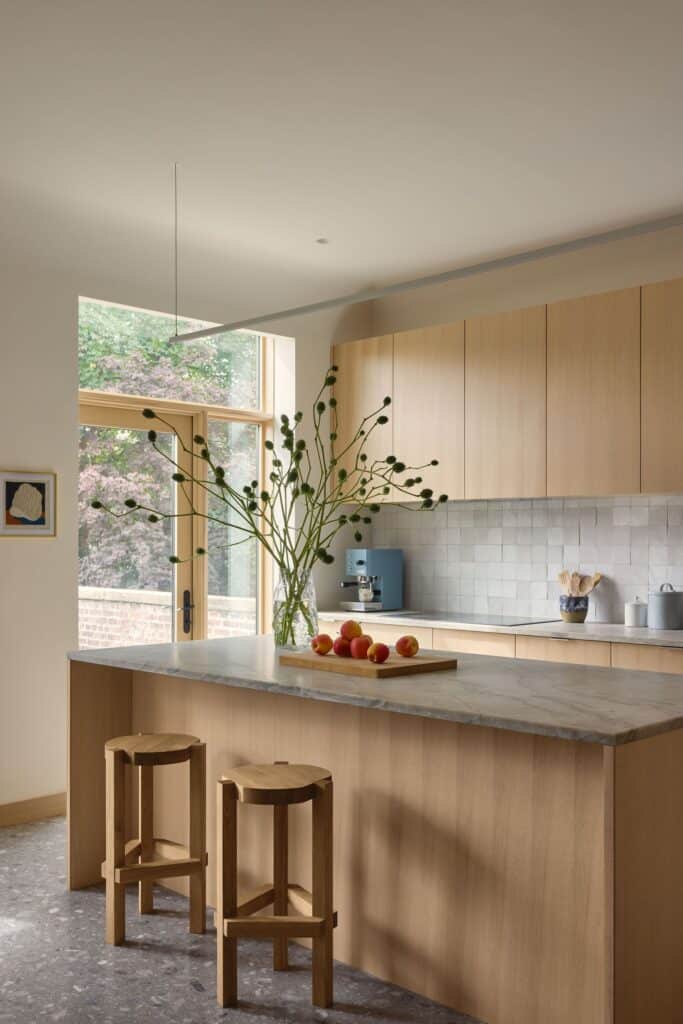 A contemporary kitchen with light wood cabinetry, a quartzite island, and handmade tile backsplash.