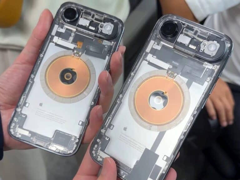 Two modified iPhones with fully transparent glass backs showing internal copper charging coils and battery components.