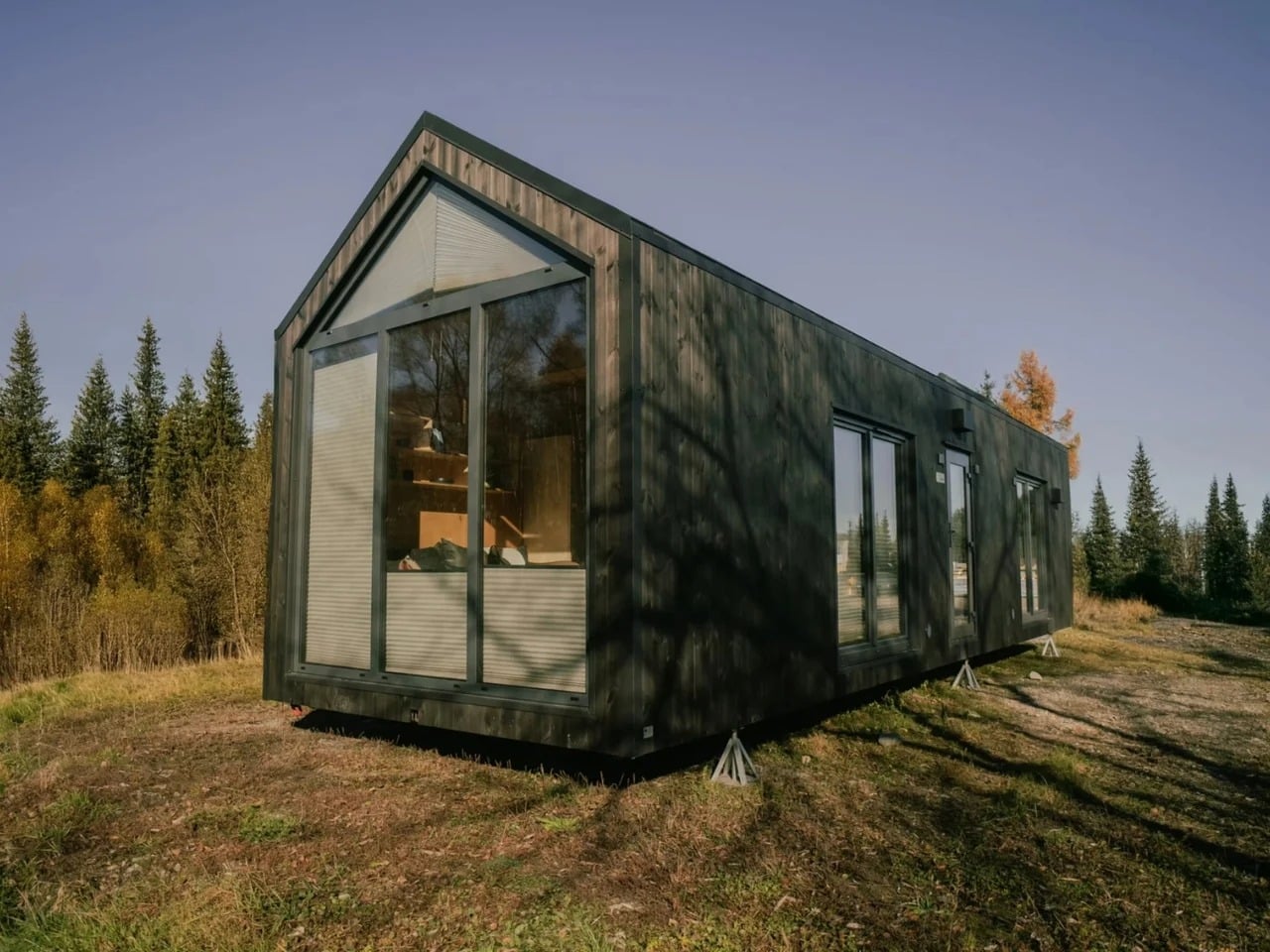 Exterior of Zenith tiny house featuring dark wood cladding, large floor-to-ceiling windows, and a modern gabled roof design.