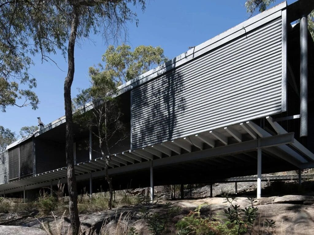 Low-angle shot of the Ball-Eastaway House supported by slender steel stilts over natural rock formations.