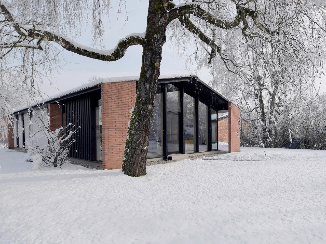 Modern residential architecture with brick pillars and large glass facades surrounded by snow and poplar trees.