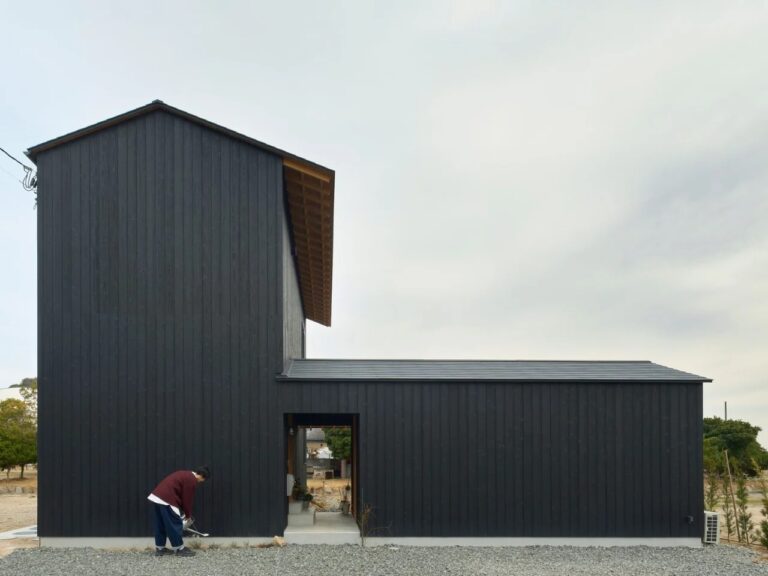 Minimalist dark charred wood facade of Onomichi House by Studio Bark in Japan, featuring Yakisugi cladding and a central sheltered entrance.