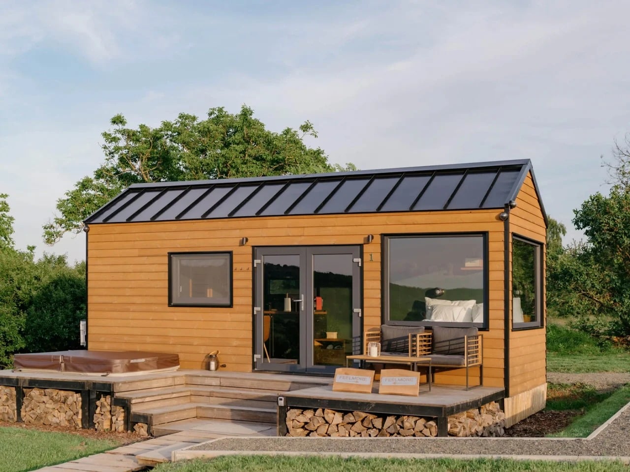 Exterior view of Tiny Amsterdam house featuring wood cladding, a black metal roof, and an outdoor wooden deck with a hot tub.
