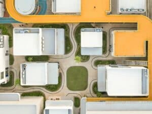 Aerial top-down view of My Front Yard project showing white modular pavilions, curved walking paths, and a prominent yellow elevated walkway.