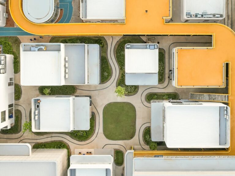 Aerial top-down view of My Front Yard project showing white modular pavilions, curved walking paths, and a prominent yellow elevated walkway.