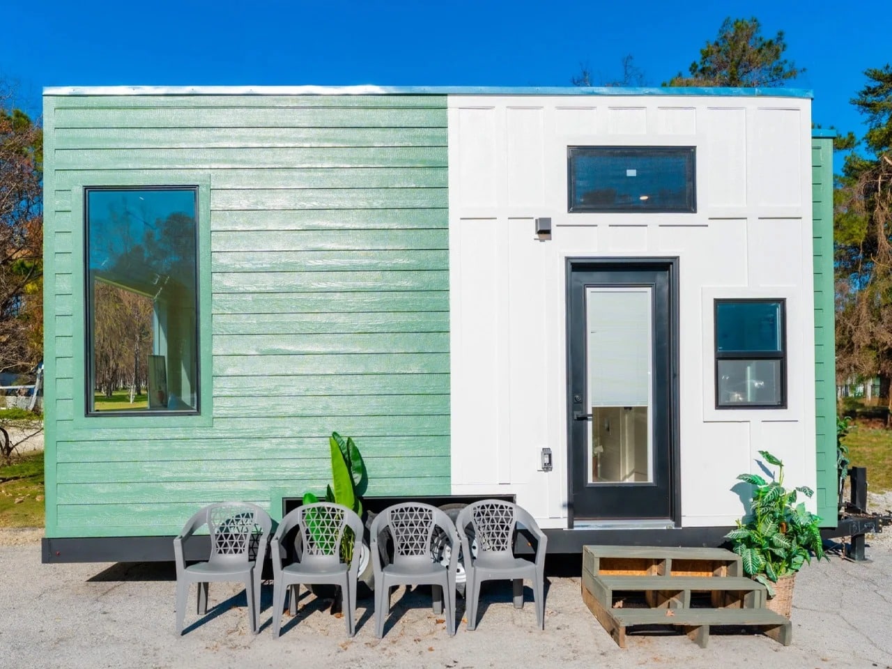 Exterior view of the Sora 20 foot tiny home featuring green horizontal siding and white vertical panels on a mobile trailer.