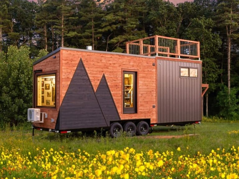 Exterior view of The Park tiny home on wheels featuring cedar siding with a mountain-shaped dark wood inlay and a rooftop deck.