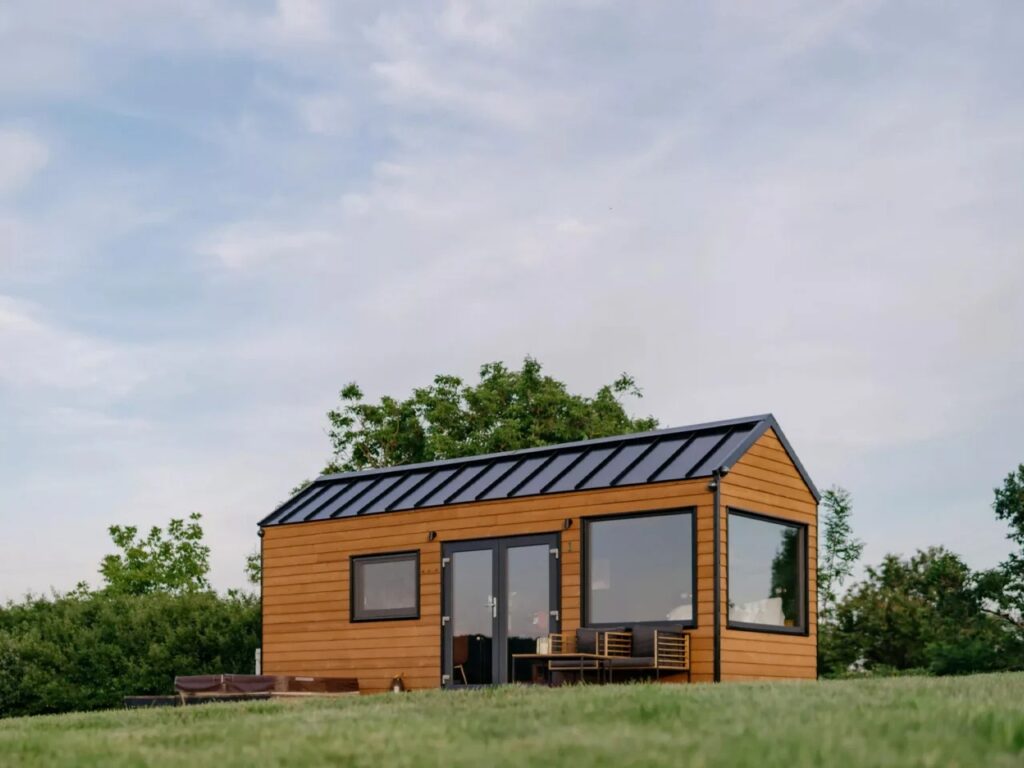 Low-angle shot of the Tiny Amsterdam mobile home on a grassy field against a cloudy sky.