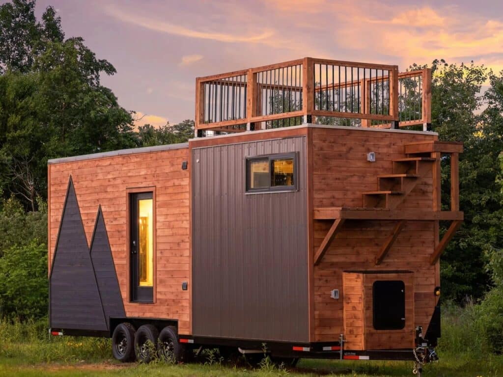 Side view of The Park tiny home showing the exterior wooden staircase leading to the accessible rooftop terrace.