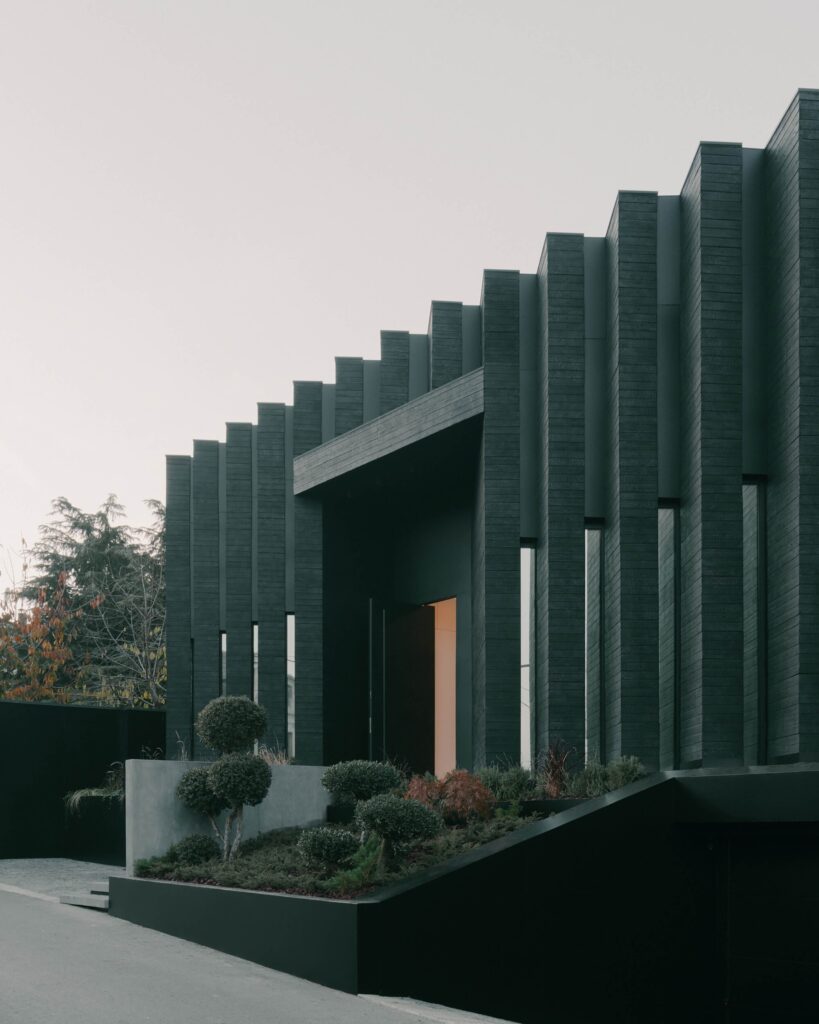 Close-up of the rhythmic charred wood facade and integrated planter box at the Okrokana residence.