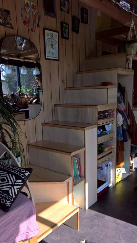 A multi-functional wooden staircase in the Chillhouse with built-in storage drawers and shelves to optimize space.
