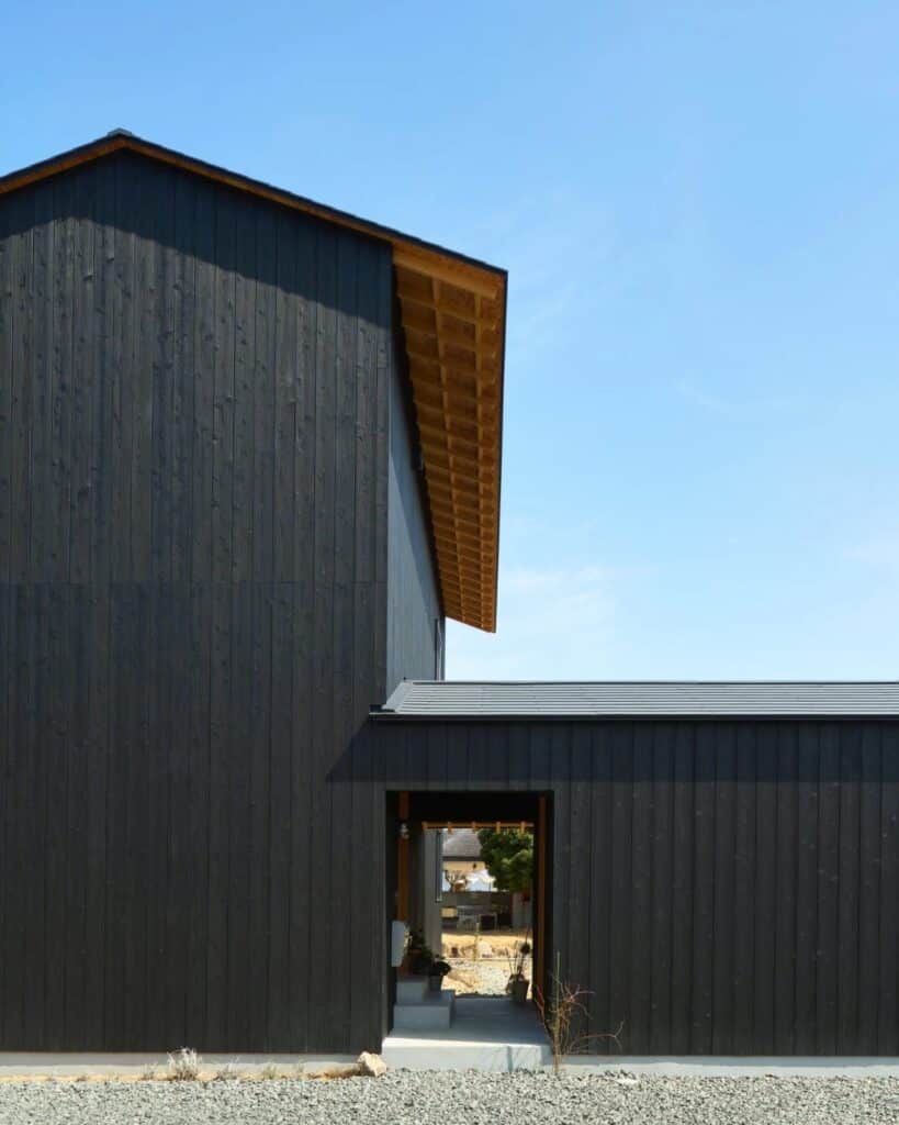 Close-up of the Yakisugi charred wood cladding on the two-story main building of Onomichi House, highlighting the vertical timber texture.