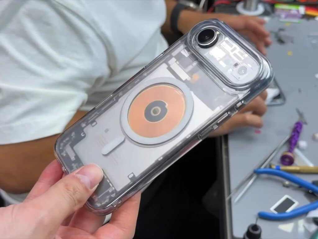 Tilted view of a transparent iPhone reflecting light on its modified glass surface in a workshop.