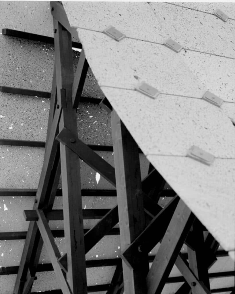Black and white close-up detail of the charred timber joints and the underside of the lava stone roof tiles.