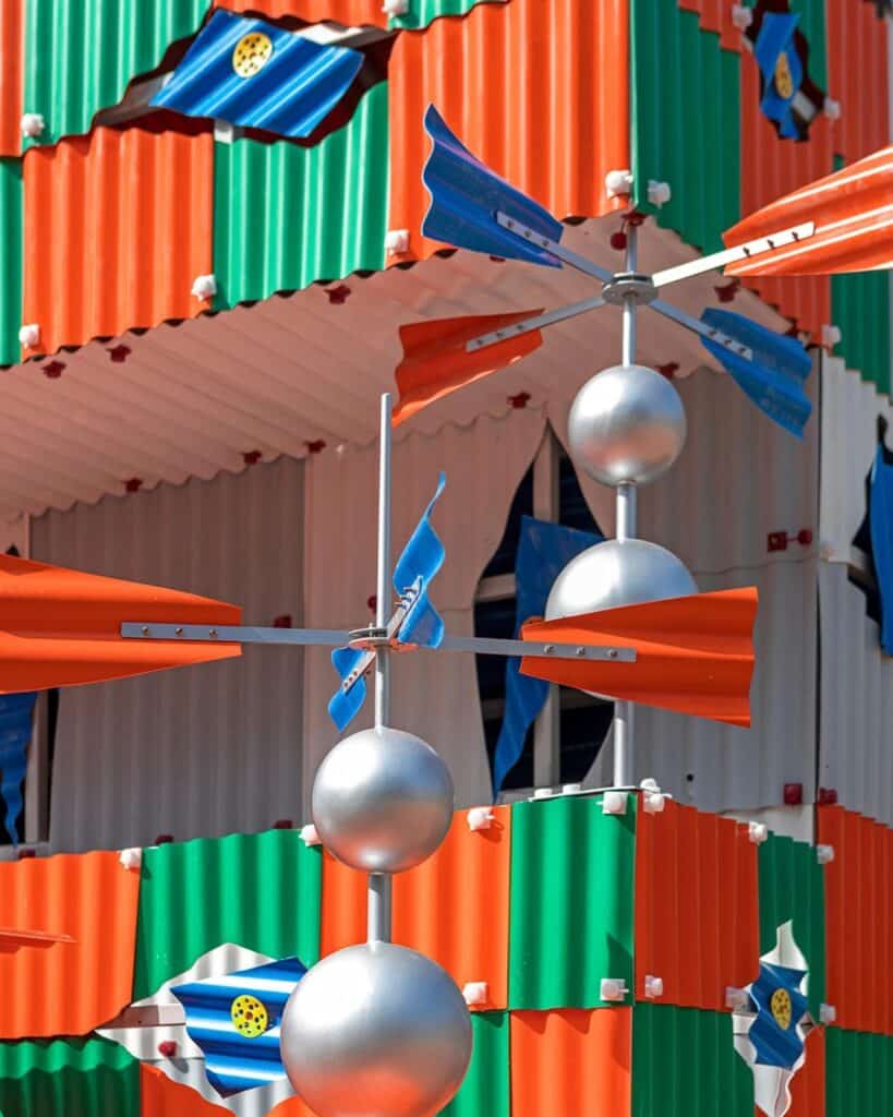 Detail of silver spherical weather vanes and orange kinetic fins attached to the colorful corrugated exterior of Clock House No. 2.