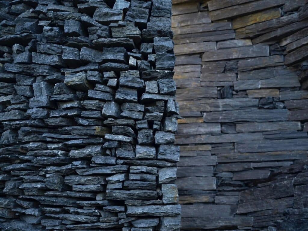 Extreme close-up of stacked dark schist stone layers showing the rough texture and precision of the dry stone construction.