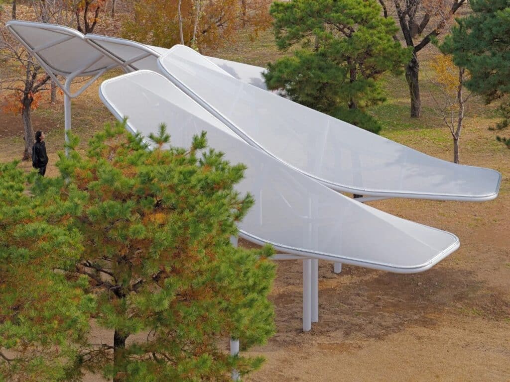 Aerial view of Seoul Wing shade structures in a park, mimicking bird wings with overlapping white panels and organic steel supports.
