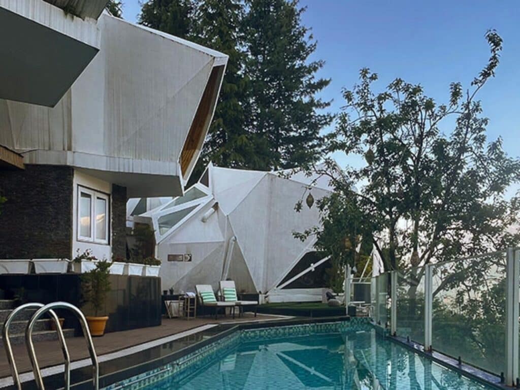 Infinity pool at Ayla resort overlooking the Naggar Valley mountains with white pods in the background.