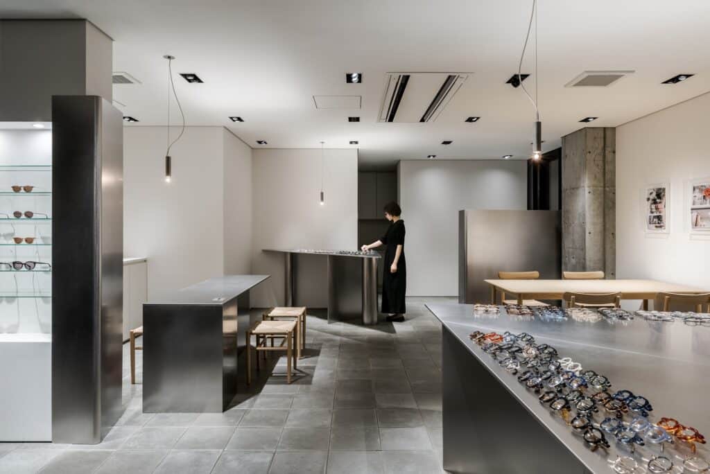 Wide shot of Ashiya Optical Store interior showing the relationship between display areas, seating, and concrete structural elements.