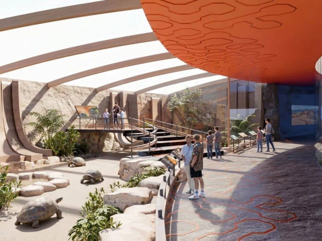 Indoor interactive exhibit for giant tortoises in the Fire zone of House of Elements with rocky terrain and orange ceiling patterns.