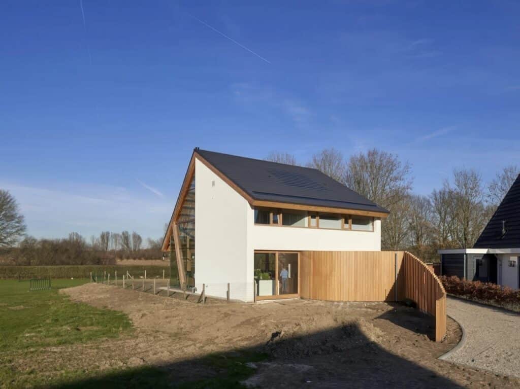 Side view of the Dutch catalog house showing the contrast between solid white service walls and open glass living sections.
