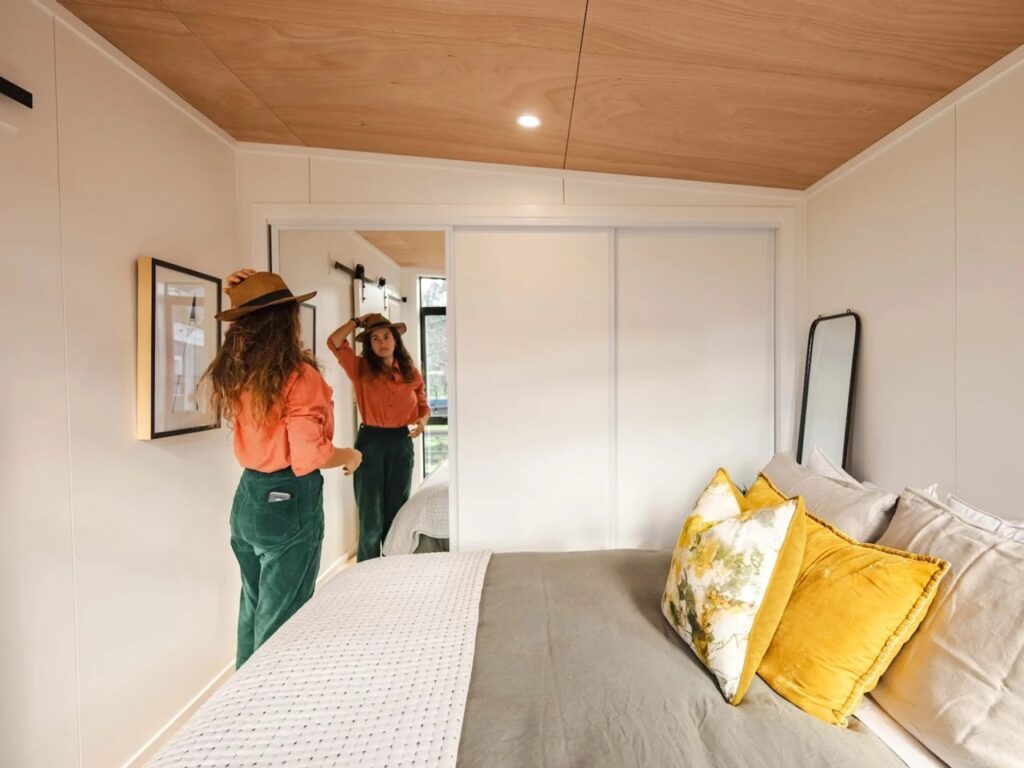 Compact bedroom with a large mirrored sliding closet and warm plywood ceiling.