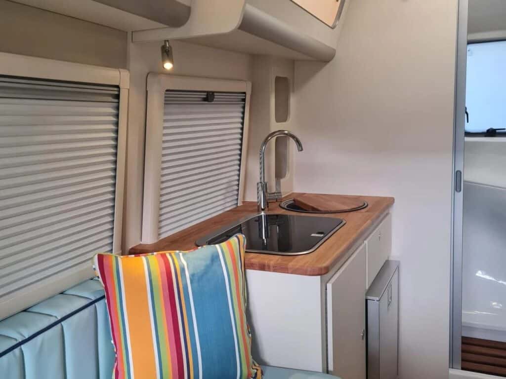 Close-up of the compact kitchenette in the Bothy caravan with a stainless steel sink and wooden countertop.