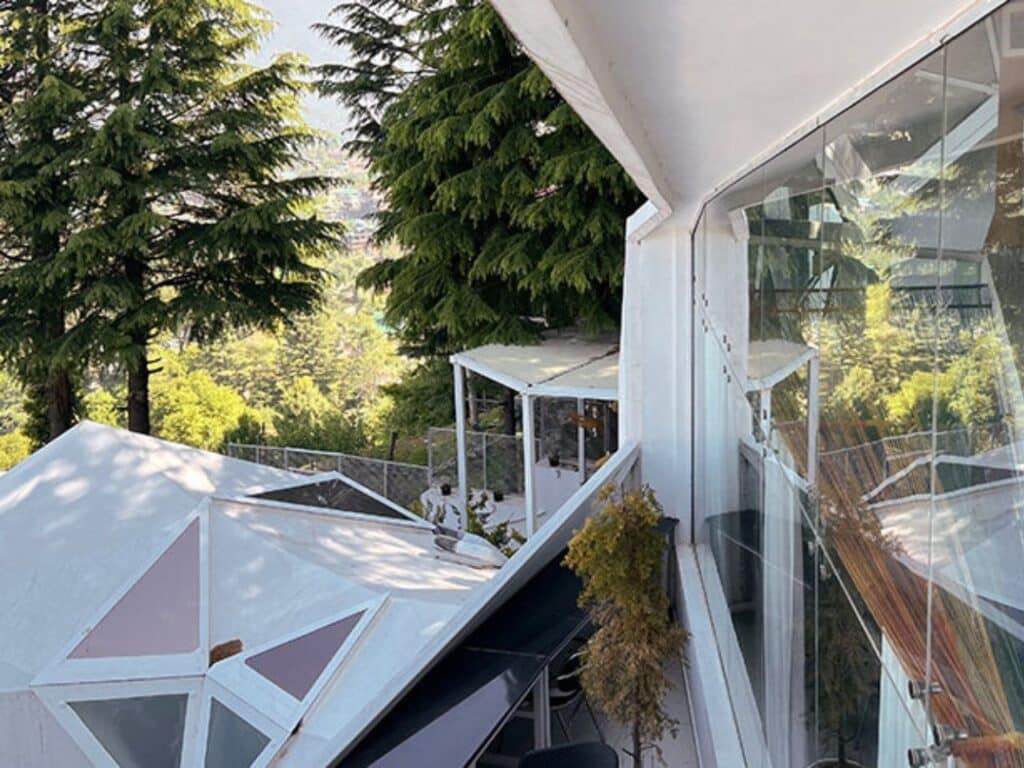 A balcony view from the resort showing the tiered structure and white faceted roofs overlooking the green forest.