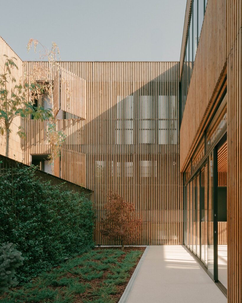 View of the internal garden and courtyard showing the transition between natural wood slats and lush greenery.