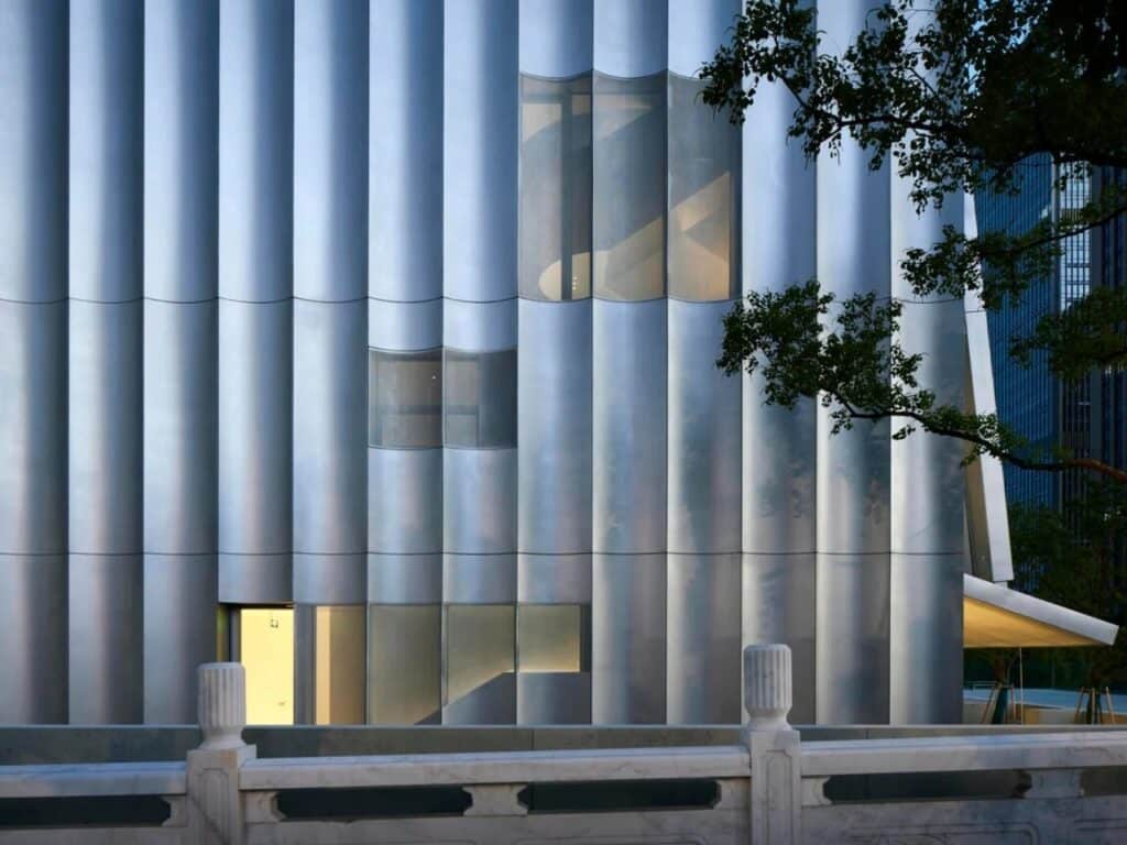 Vertical facade detail of the Empathy Museum showing recessed windows and curved metallic cladding.