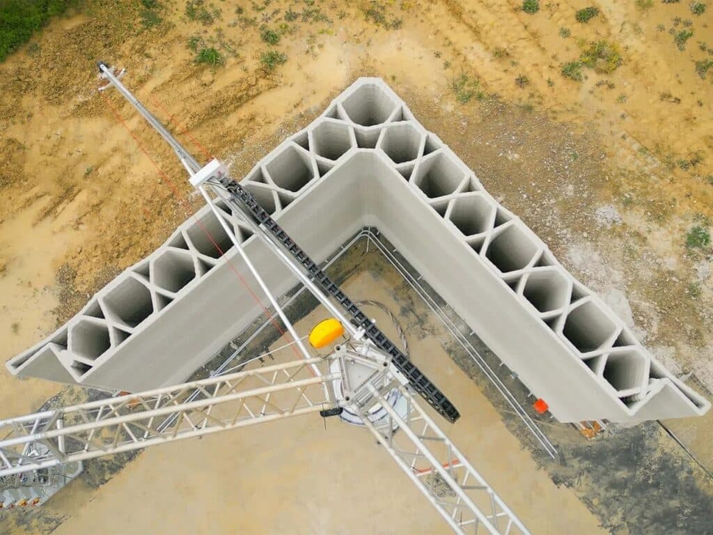 Top-down view of a 3D-printed wall corner showing the triangular honeycomb internal structure for stability and insulation.