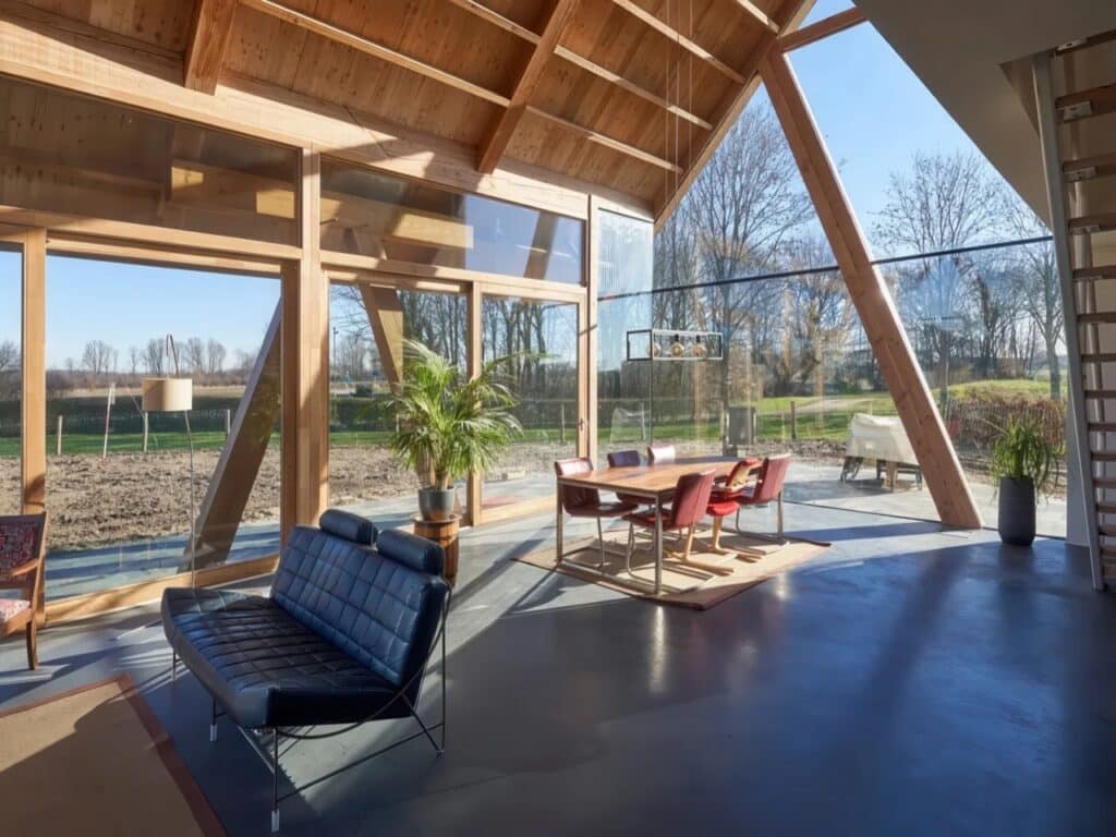 Interior dining area with high gabled wooden ceilings, inclined timber columns, and polished concrete floors.