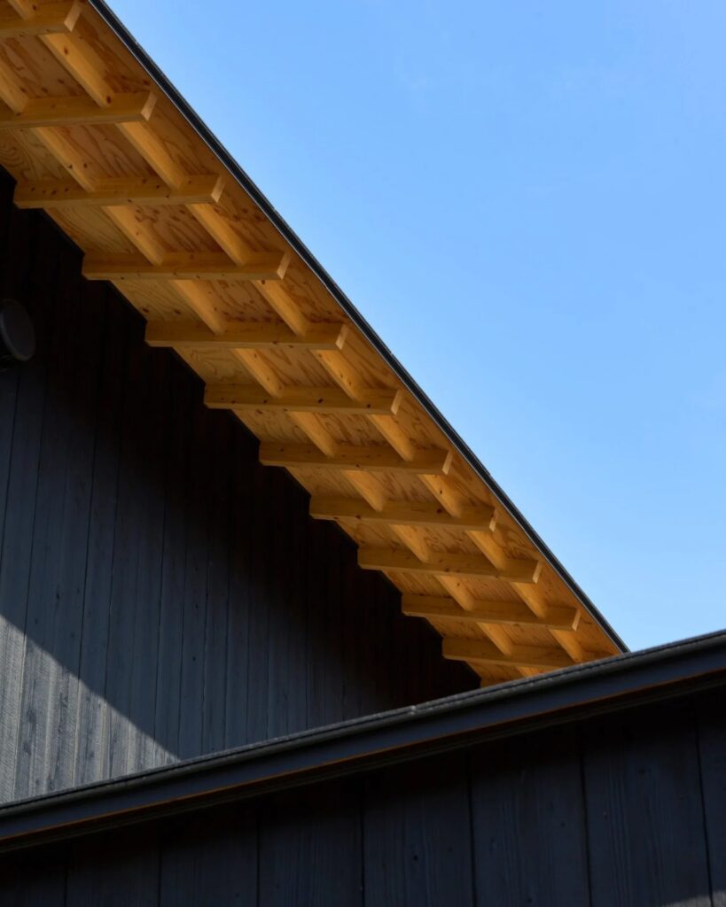 Architectural detail of the exposed wooden roof rafters and eaves of Onomichi House, showcasing traditional Japanese carpentry influences.