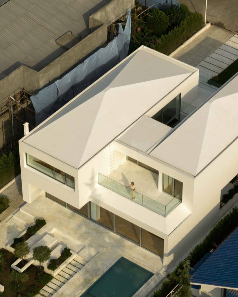 High-angle shot of a villa's back terrace, swimming pool, and minimalist landscaping.