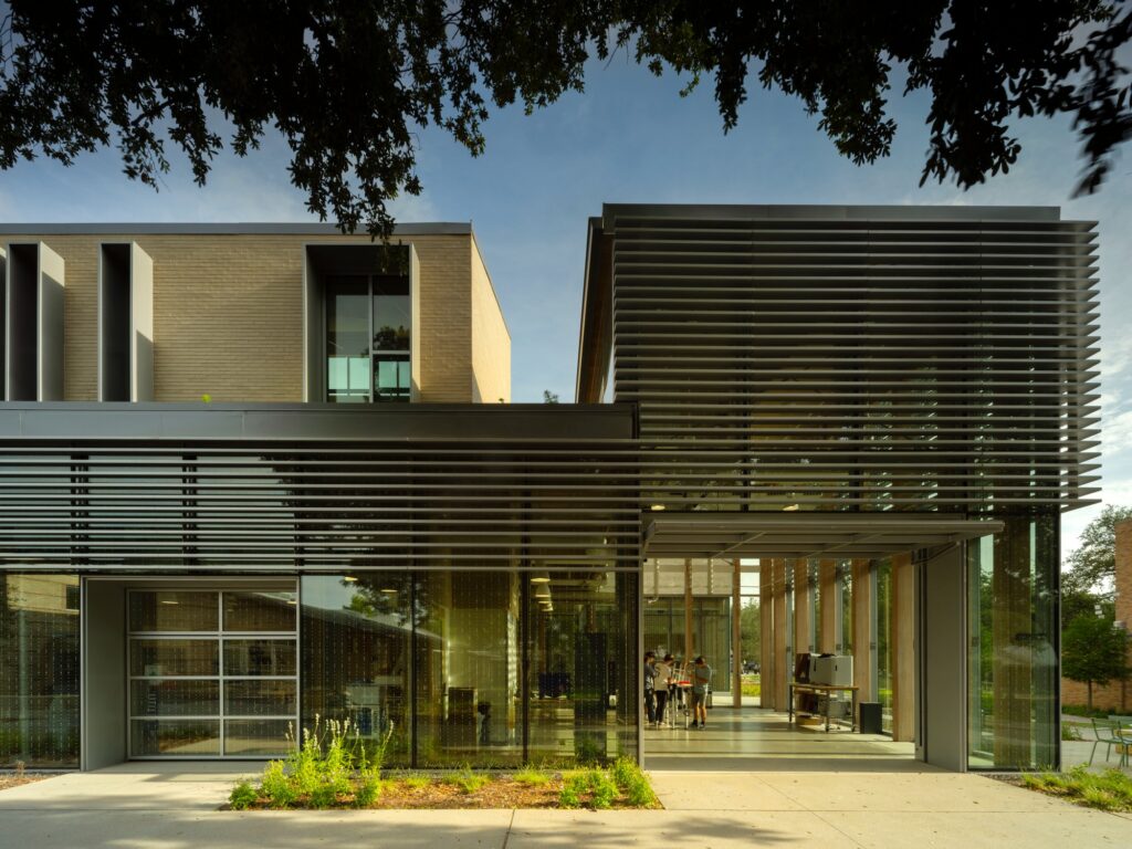 Close-up of the STEM center's glass and metal facade featuring a garage-style door for the robotics lab and exterior sun louvers.