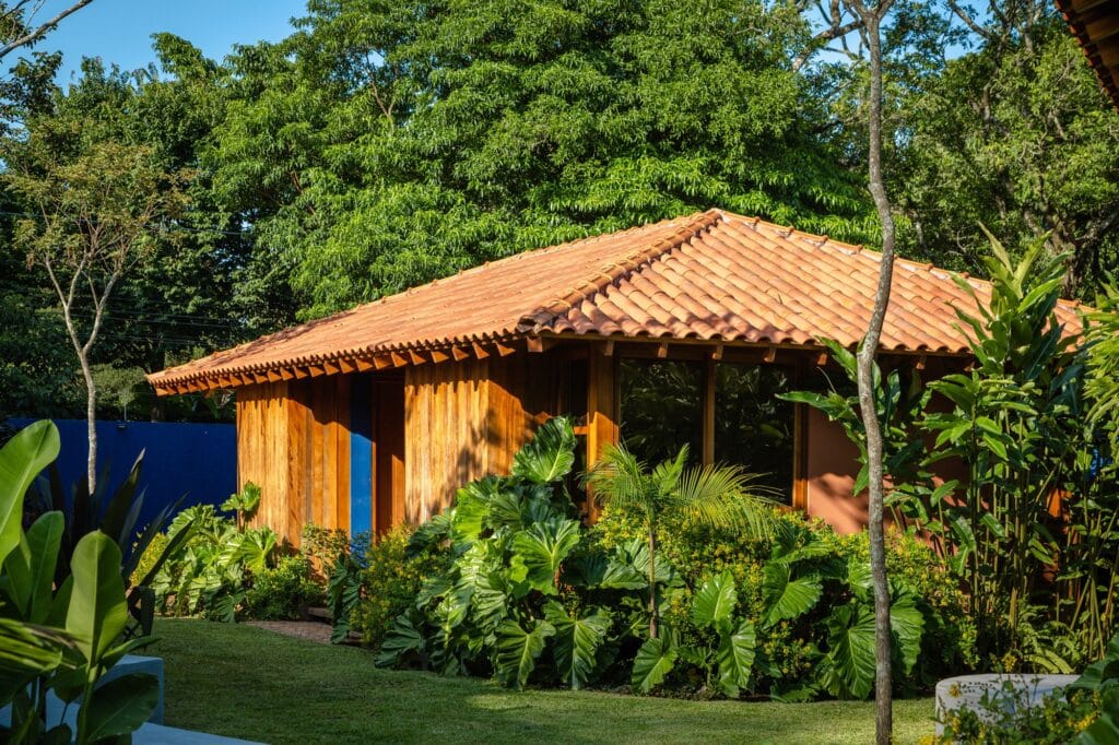 A small wooden guest wing with a traditional pitched roof nestled among dense tropical foliage.