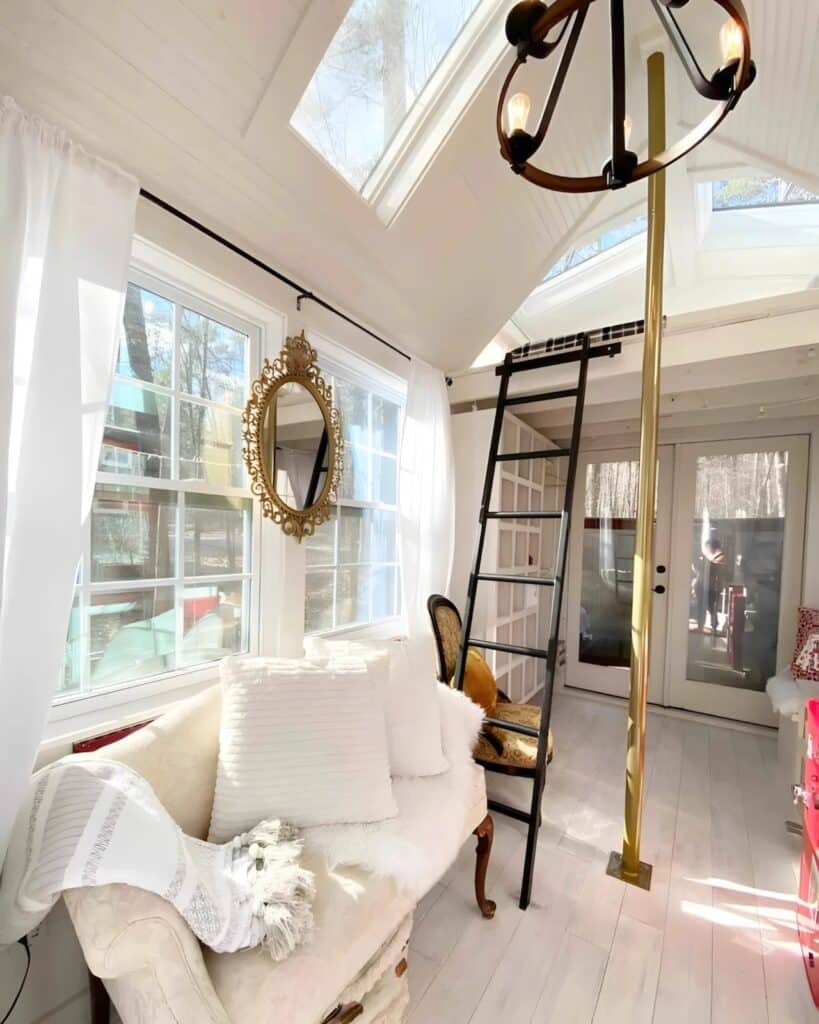Living area of a tiny house featuring a brass fire pole, a white sofa, and a black ladder leading to the loft.