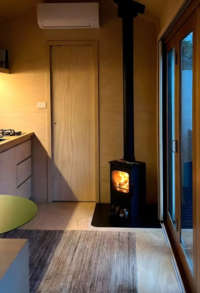 Modern wood-burning stove near the cabin entrance, providing warmth to the wooden interior.