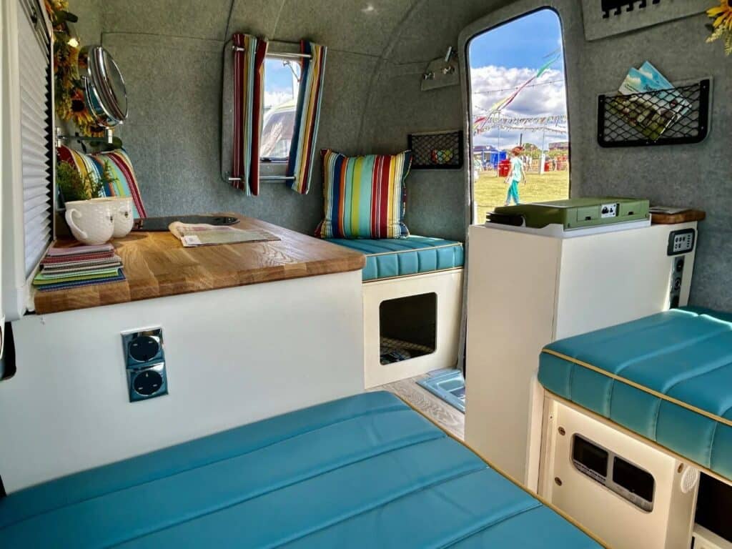 Wide interior shot of the Bothy caravan cabin showing storage pockets, power outlets, and the open door.