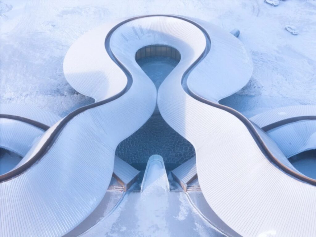 Symmetrical top-down view of the winding roof structure meeting at a central point, covered in snow.