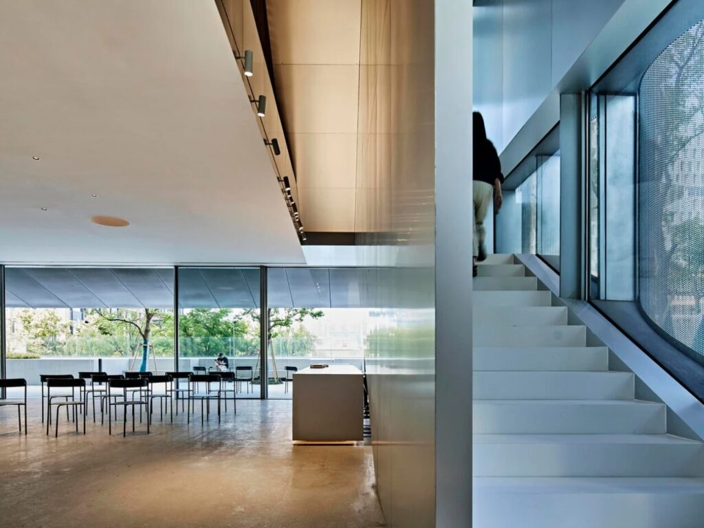 Interior staircase of the Empathy Museum with bright white finish and view to the outside through a glass wall.