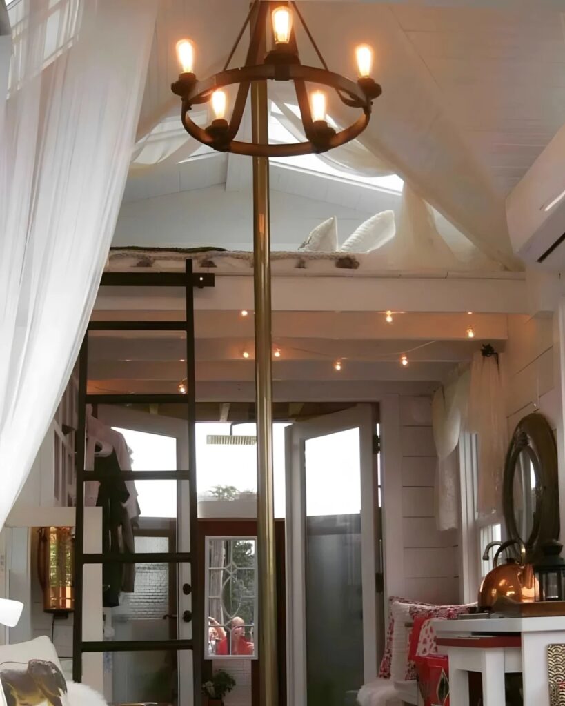 View from the ground floor looking up at a circular chandelier and the brass fire pole stretching to the ceiling.