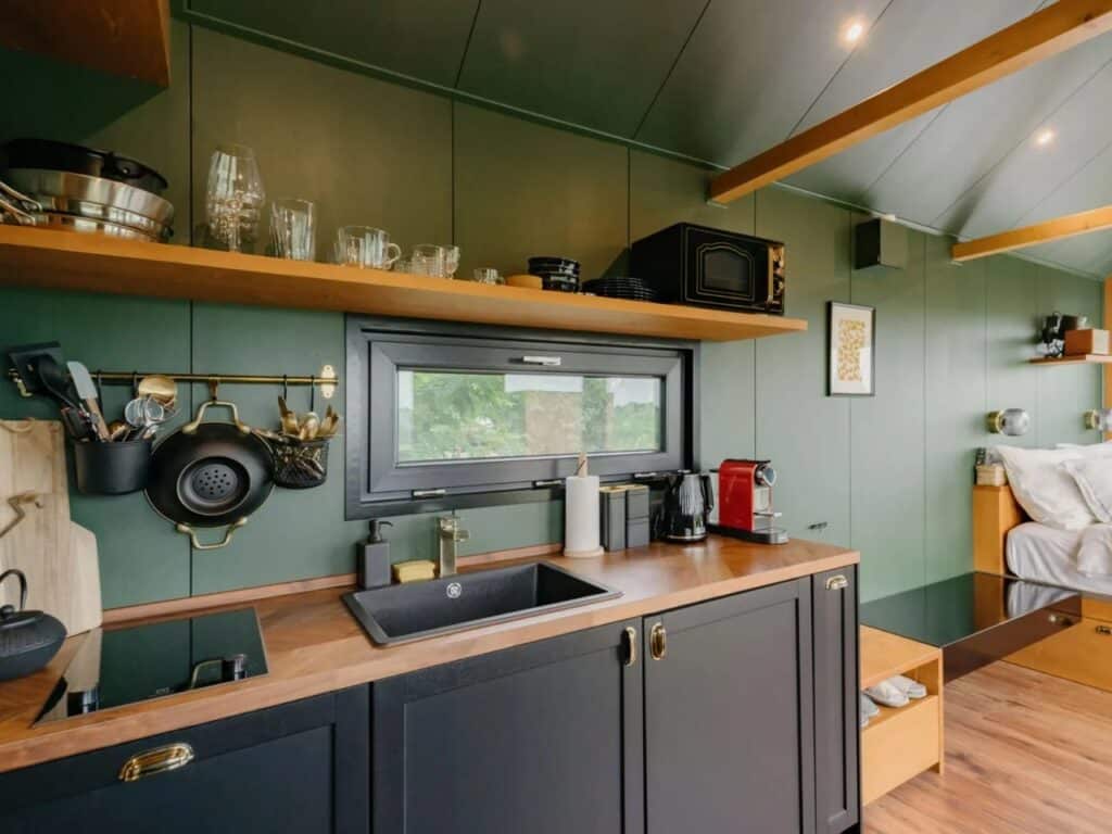 Modern compact kitchen in Tiny Amsterdam with dark cabinets, wooden countertops, and integrated appliances.