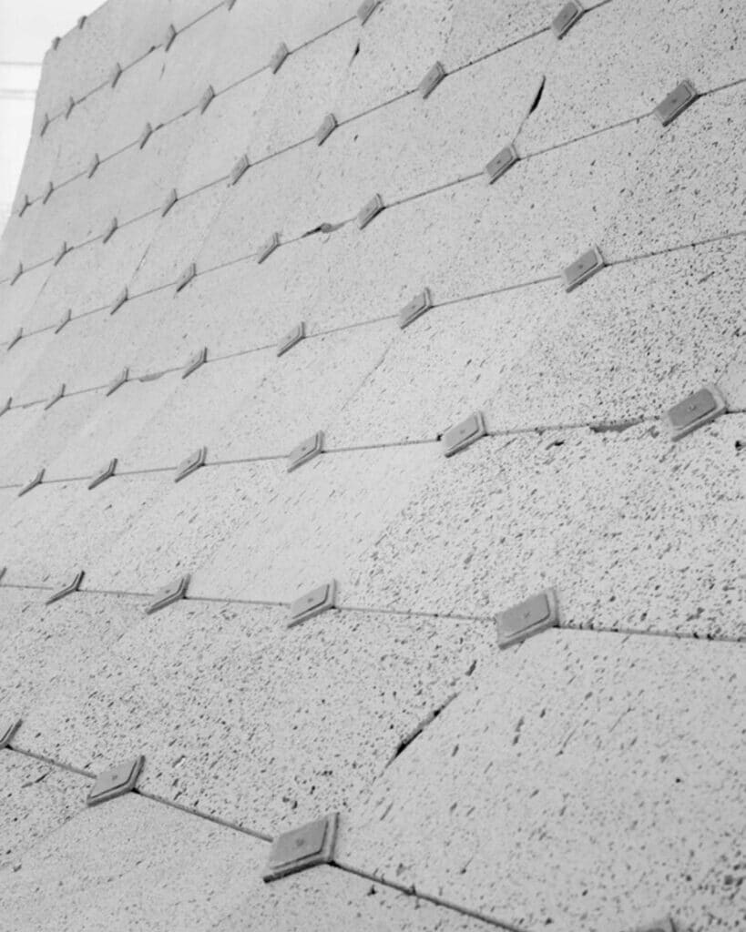 Angled black and white close-up of the textured roof tiles, emphasizing the rhythmic pattern of the fasteners.