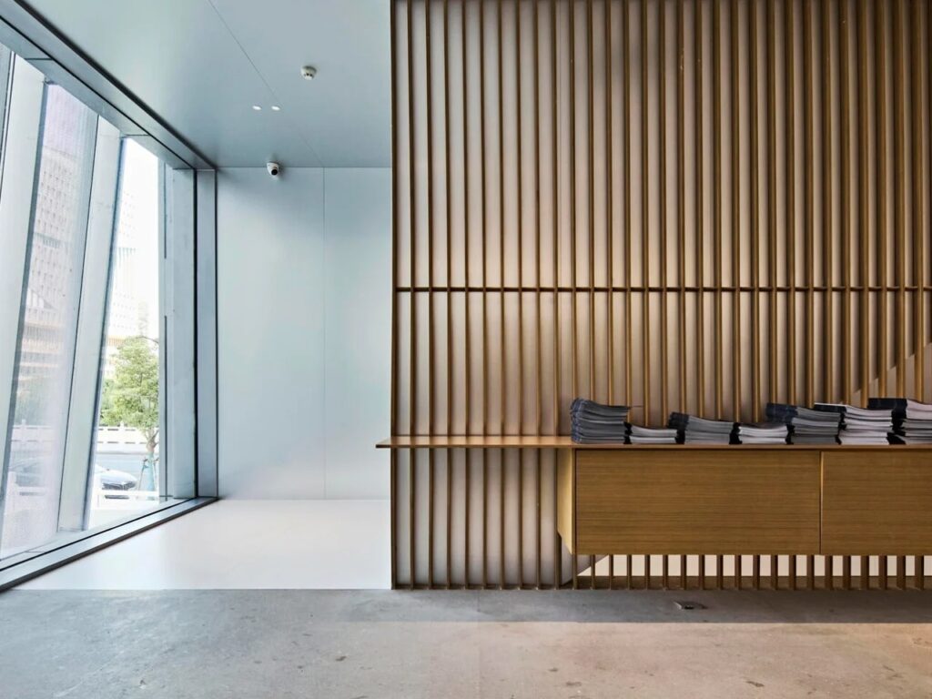 Interior detail showing a wooden slatted partition and reception desk in the Hangzhou Empathy Museum.