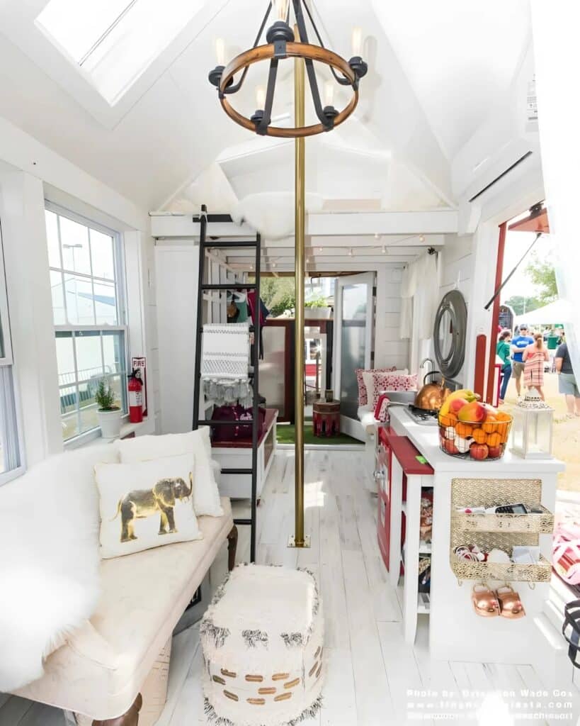 Full interior view of the tiny firehouse showing the living room, kitchen, fire pole, and loft ladder in one bright space.